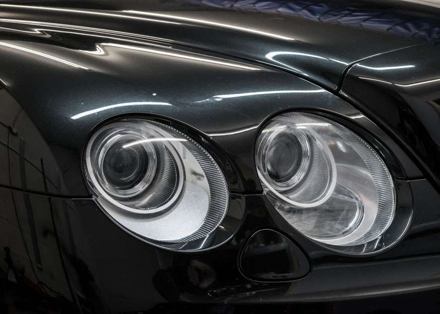 Close up shot of left side Bentley Flying Spur cloudy/foggy headlight before headlight restoration