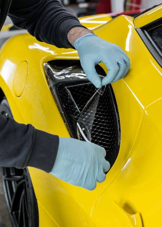 Paint protection film (PPF) being applied to side intake of yellow Ferrari 488 Pista