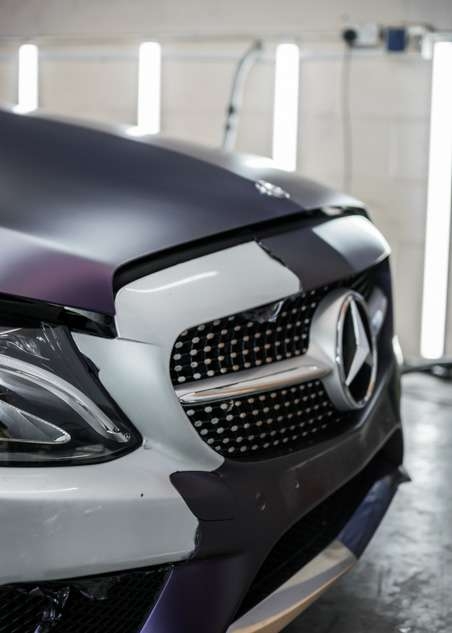 Purple vinyl wrap being removed from car grey Mercedes C Class